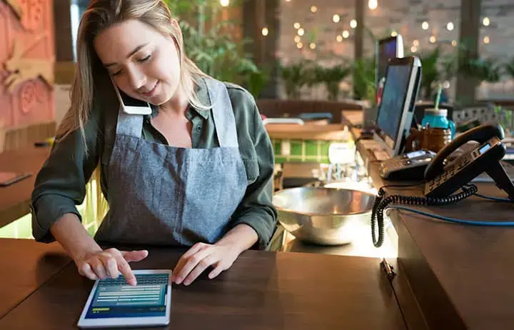 Restaurant owner using phone and ipad at front counter
