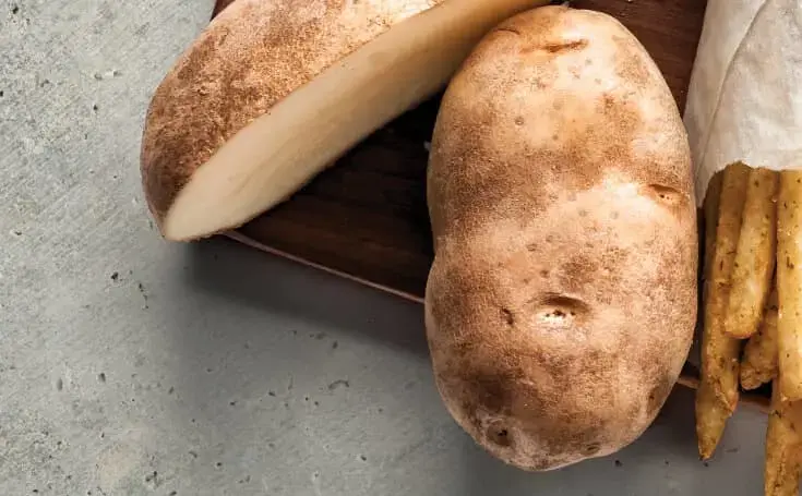 A sliced and whole raw potato with fries